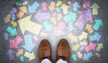 Kahverengi deri ayakkabılar ve çeşitli yönlerde renkli tebeşir okları. Kaos konsepti.