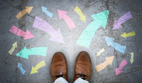 Stock image Brown leather shoes and many colorful chalky arrows in various directions - chaos concept