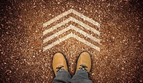 Yellow leather shoes and one geometrical chalky arrow on ground - destination concept
