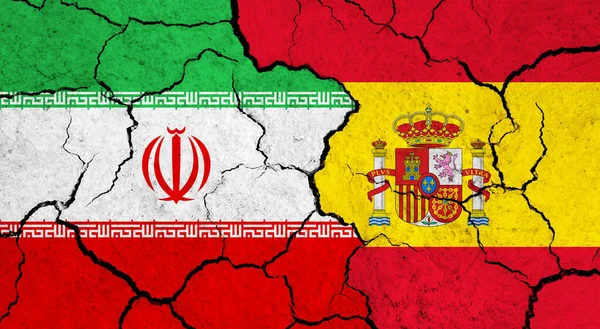 Flags of Iran and Spain on cracked surface - politics, relationship concept