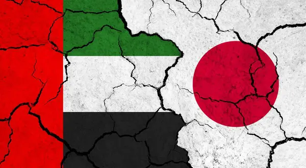 Flags of United Arab Emirates and Japan on cracked surface - politics, relationship concept
