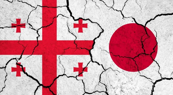 Flags of Georgia and Japan on cracked surface - politics, relationship concept