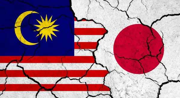Flags of Malaysia and Japan on cracked surface - politics, relationship concept