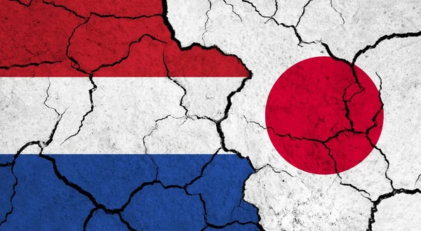 Flags of Netherlands and Japan on cracked surface - politics, relationship concept