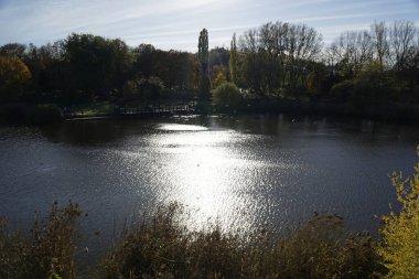 Sonbaharda parktaki göl ve suya yansıyan güneş