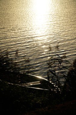 Sahilde eski ahşap bir tekne, arka planda günbatımı