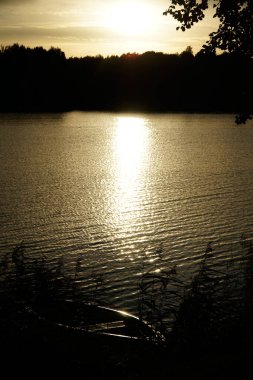 Sahilde eski ahşap bir tekne, arka planda günbatımı