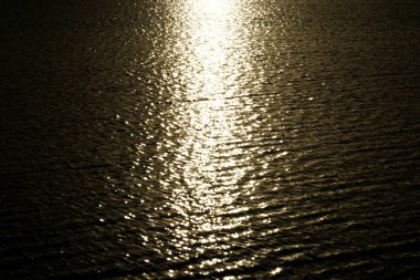 Güneş gün batımında su yüzeyine yansıyor.