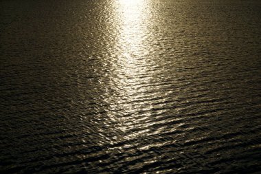 Güneş gün batımında su yüzeyine yansıyor.