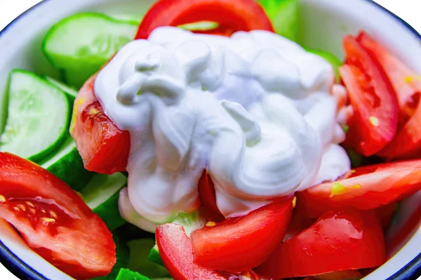 Fresh vegetable salad of tomatoes and cucumbers with sour cream in a plate. Red tomato. Green cucumber. White sour cream. Vegetable salad. Vegetarian food. Healthy food. The beauty.