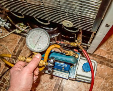 Tamir sırasında soğutma ünitesinin vakum pompası. Buzdolabı tamiri. Süpürge pompası. Basınç göstergesi. Soğutma ünitesi motoru. Servis bakımı. Ev aletleri tamir atölyesi.