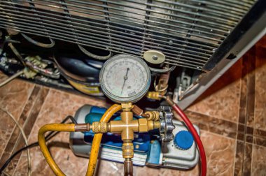 Tamir sırasında soğutma ünitesinin vakum pompası. Buzdolabı tamiri. Süpürge pompası. Basınç göstergesi. Soğutma ünitesi motoru. Servis bakımı. Ev aletleri tamir atölyesi.