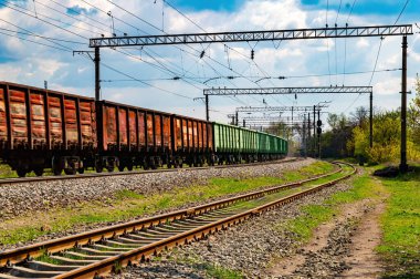 Tren raylarında yük treninin vagonlarını taşımak. Demiryolu taşımacılığı. Nakliye işi. Malların nakliyesi. Malların endüstriyel taşımacılığı. Tren vagonları..
