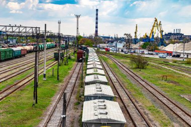 Tren raylarında yük treninin vagonlarını taşımak. Demiryolu taşımacılığı. Nakliye işi. Malların nakliyesi. Malların endüstriyel taşımacılığı. Tren vagonları..