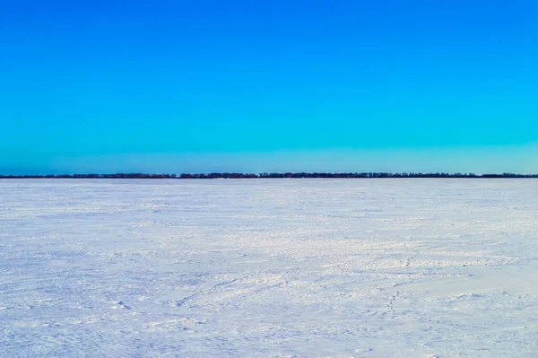 青い空に対して冬の白い雪に覆われたフィールド 白い雪だ 青い空だ 曇った地平線 農業分野 冬の季節 自然の風景 背景画像 — ストック写真