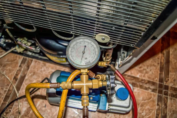 Tamir sırasında soğutma ünitesinin vakum pompası. Buzdolabı tamiri. Süpürge pompası. Basınç göstergesi. Soğutma ünitesi motoru. Servis bakımı. Ev aletleri tamir atölyesi.
