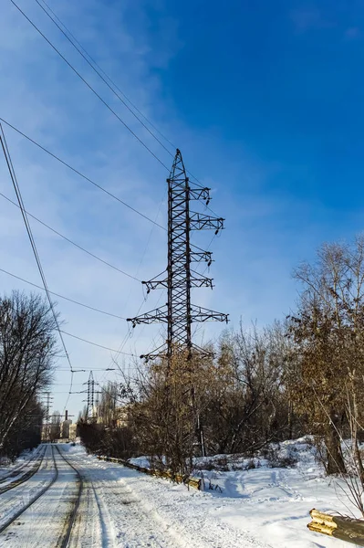 Yüksek voltajlı elektrik kabloları olan kule. Elektrik iletim hattı. Kablolu bir direk. Sanayi enerji mühendisliği. Mavi gökyüzü. Beyaz bulutlar. Sanayi manzarası.