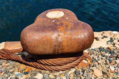 Gemilerin iskeleye demirlediği yer. Bağlama halatı. Gemi rıhtımı. Demir kabloyla metal destek. Deniz kenarında. Su alanı. Geminin limandaki park yeri. Endüstriyel tasarım.