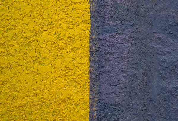 stock image The surface is painted in half in yellow and black. Paint on a concrete wall. Texture of a colored surface. Black and yellow color. background image. Template for text. Two vertical halves.