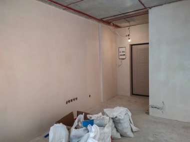 White polypropylene bags filled with construction debris in the apartment. Polypropylene bag. Construction waste. Repair in the room. Industrial waste. House cleaning after renovation.