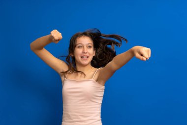 Çılgın esmer İspanyol genç atlıyor ve kaygısızca dans ediyor. Mavi stüdyo arka planında izole edilmiş güzel bir şarkının tadını çıkarıyor.