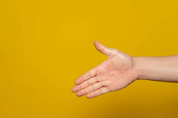 Man stretching out his hand to handshake isolated on an orange background. Mans hand ready for handshake. Alpha.