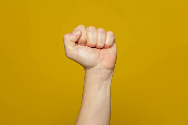 Male clenched fist, isolated on an orange background. Strong mans hand with a fist. Alpha. Protest.