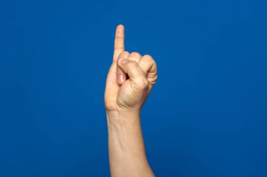 Mans hand with the little finger raised as a sign of promise or oath, isolated on blue background