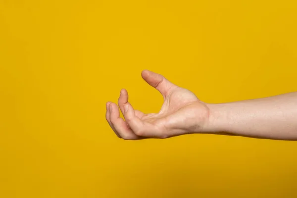Pissed off and bloodthirsty strong mans hand in the form of a claw containing anger and aggressiveness isolated on a yellow background