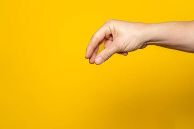 Sert adamlar el hareketleriyle sarı arka planda izole edilmiş bir nesneyi kaldırırlar.