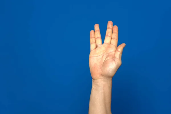アメリカの手話 男性の手は青の背景に隔離された彼の指の4で作られた文字Vを示しています — ストック写真