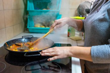 Mutfağında deniz mahsullü paella hazırlayan bir kadının yarım boy görüntüsü. Akdeniz diyet kavramı