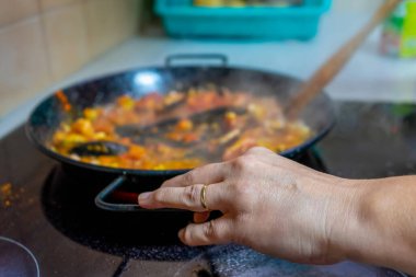 Ev sahibesi, lezzetli deniz ürünleri paella pişirirken kadın elleri. Akdeniz diyet kavramı