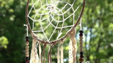 Arka planda rüya yakalayıcı ve yeşil ağaçlar var..
