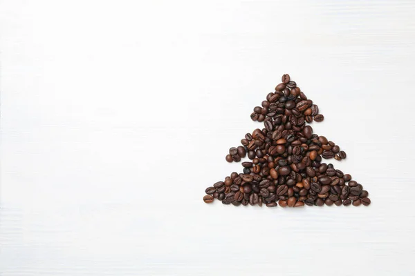 Christmas tree made of coffee seeds on white wooden background, space for text
