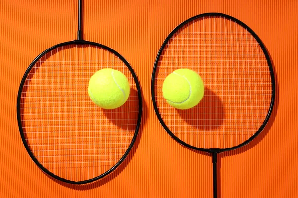 Raquetas Bádminton Pelotas Tenis Sobre Fondo Naranja Texturizado — Foto de Stock