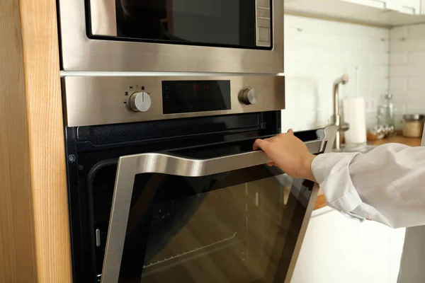 年轻女人在厨房里手打开现代烤箱 — 图库照片