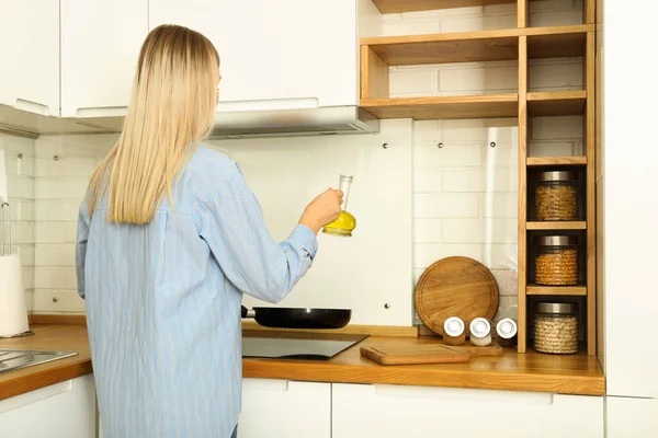 一个年轻的女人在厨房里用现代的内饰做饭 — 图库照片
