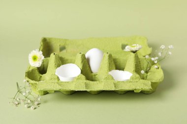 Concept of spring, eggs with flowers on green background