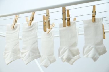 Beyaz çoraplar arka planda kuruyan askılarda asılı.