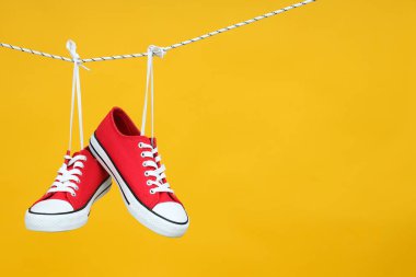 Sarı arka planda asılı kırmızı spor ayakkabılar.