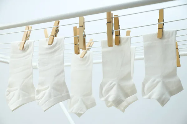 stock image White socks hanging on drying rack on light background