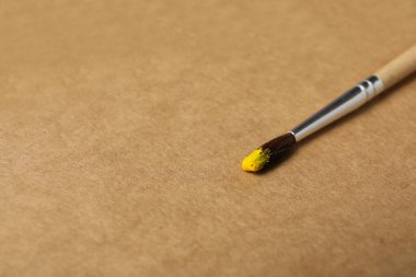 El işi arka planında sarı boya olan boya fırçası
