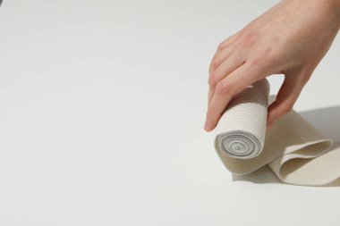 Female hand holds elastic bandage on white background