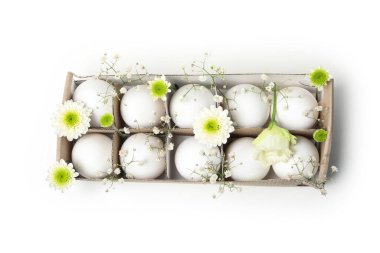 Egg box with eggs and flowers isolated on white background