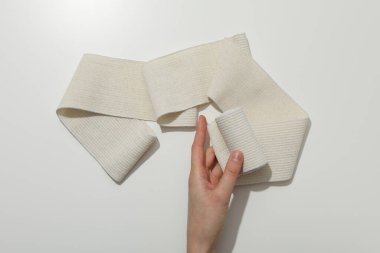 Female hand holds elastic bandage on white background