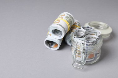Jar with Dollar bills on gray background