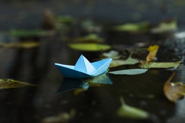Paper boat in puddle outdoor in rainy weather