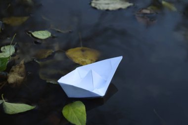 Paper boat in puddle outdoor in rainy weather