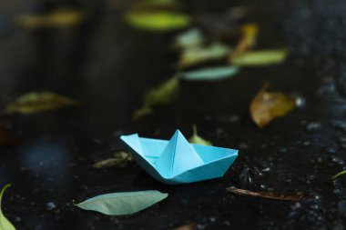 Paper boat in puddle outdoor in rainy weather